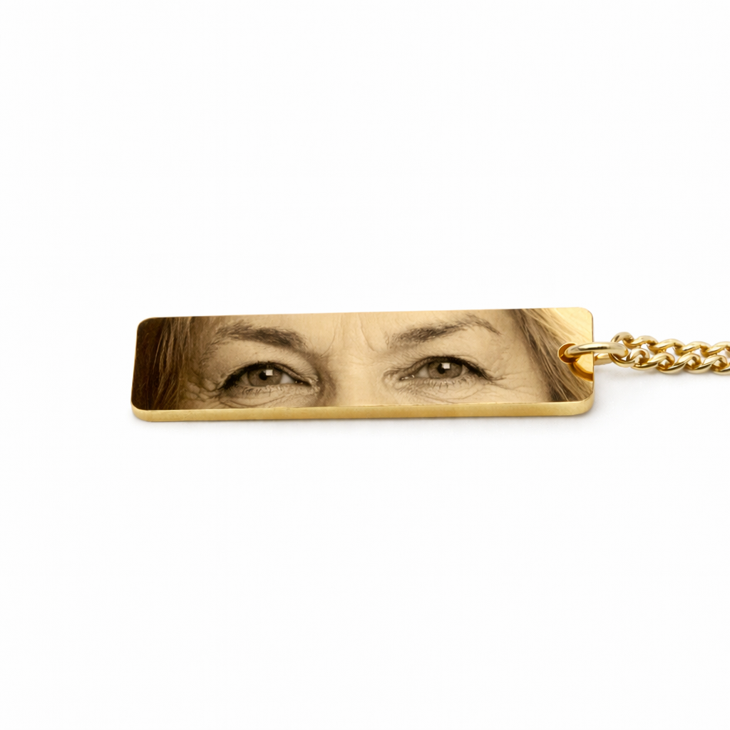 a gold keychain pendant featuring the eyes of an elderly woman who has passed in vibrant color