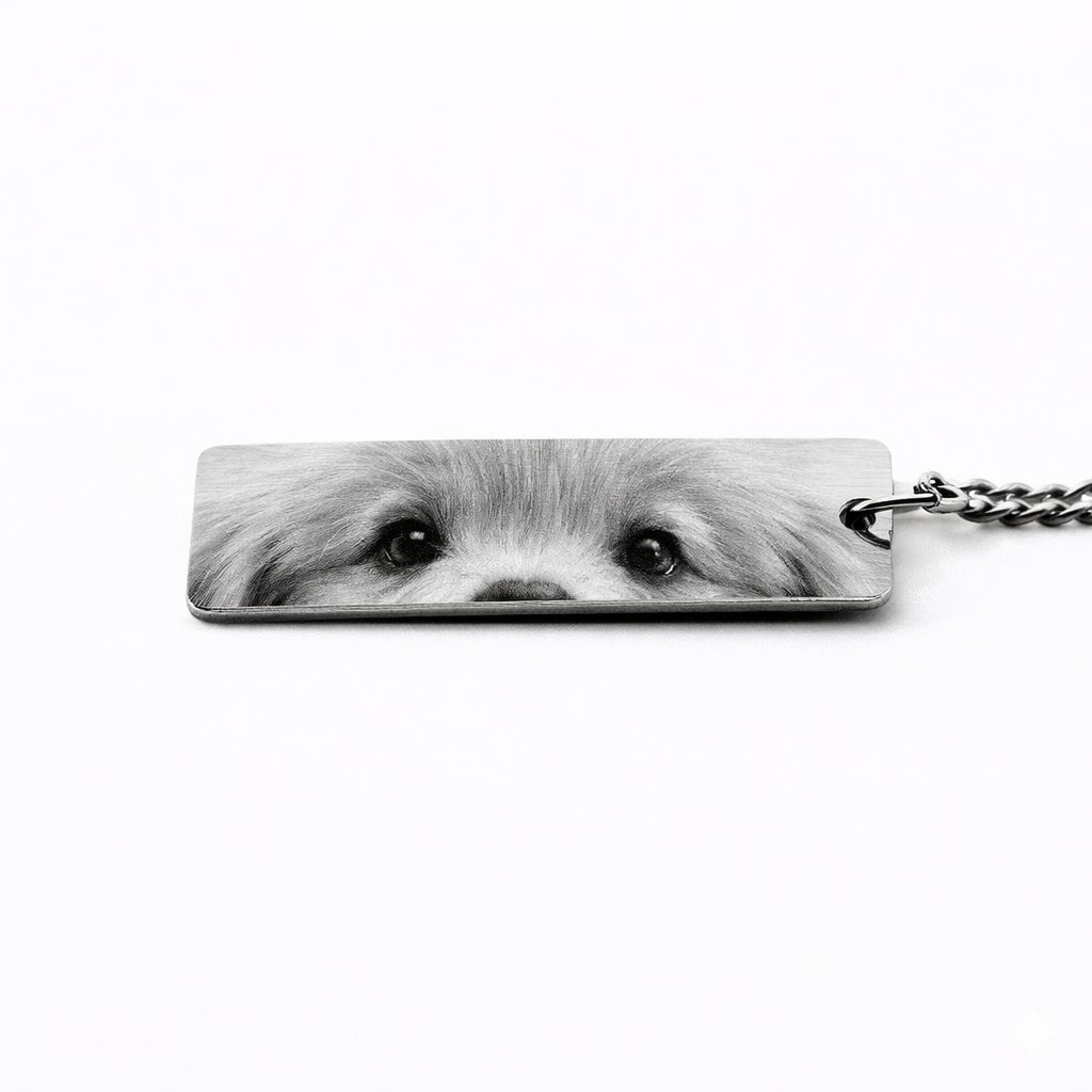 a silver keychain pendant featuring the eyes of a shi tzu puppy in greyscale