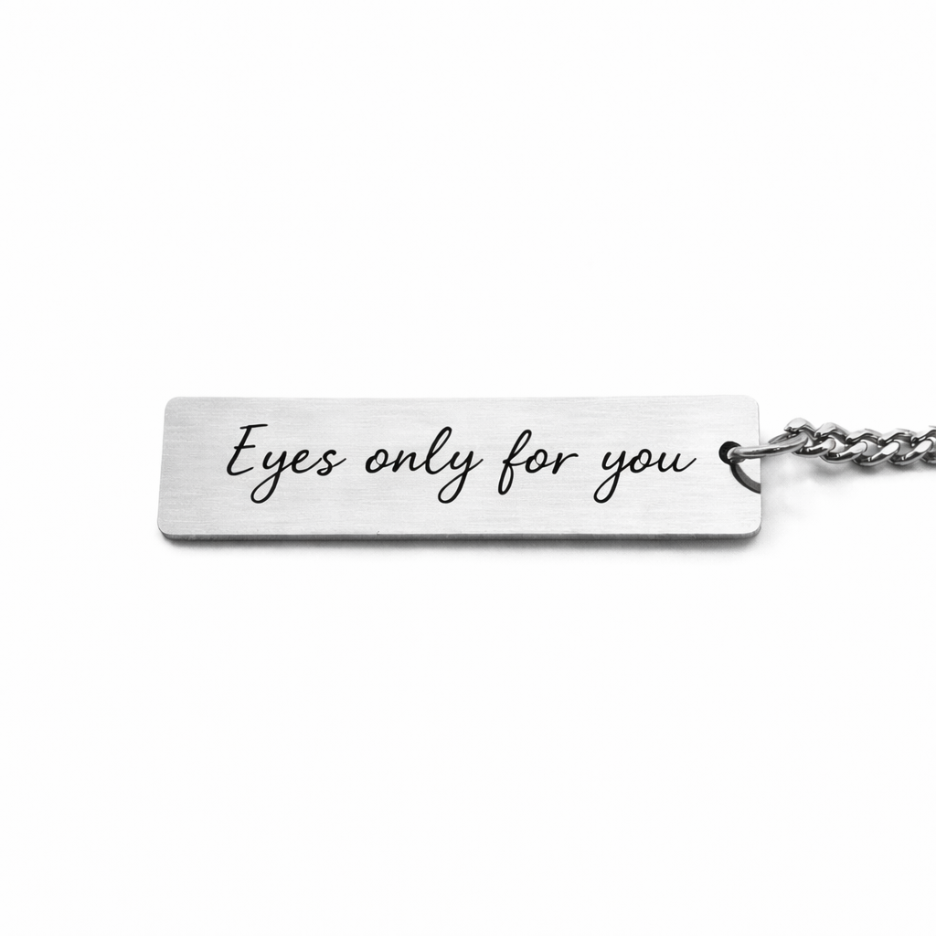 the back of a silver keychain pendant which features custom text in a casual script font, reads "eyes only for you"