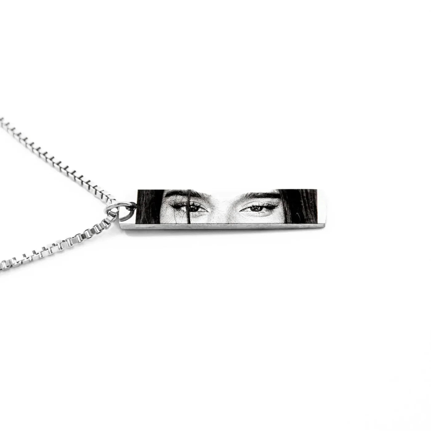 a silver necklace chain and pendant featuring the eyes of a young woman in black and white