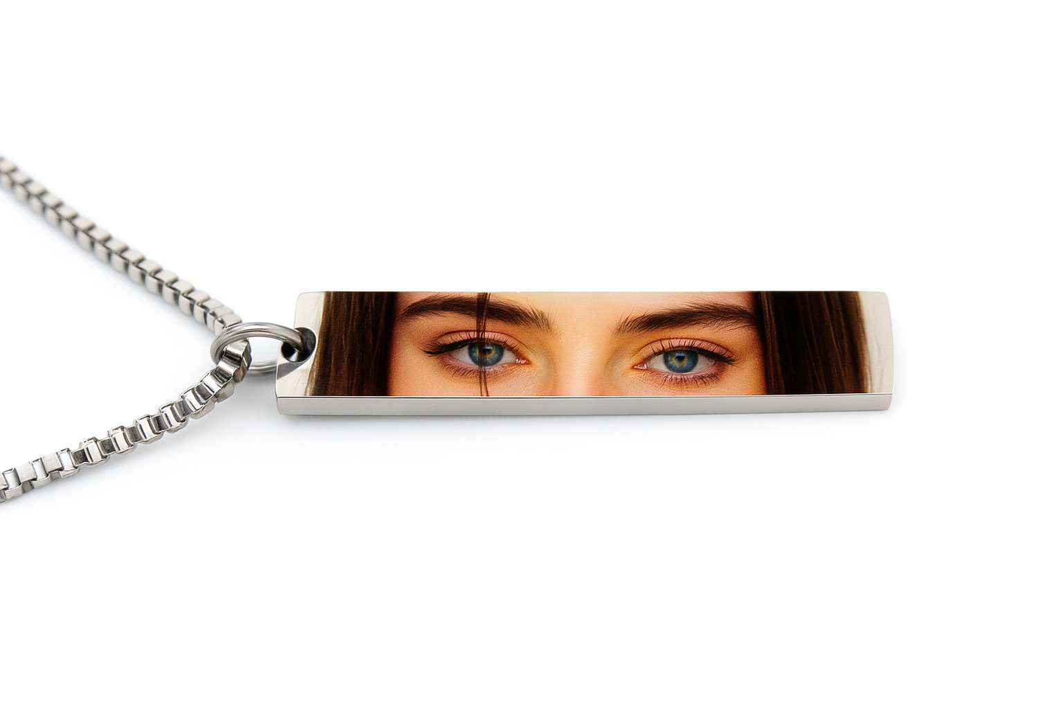 a rectangular silver necklace pendant with a printed photo of a young woman's eyes in vibrant color