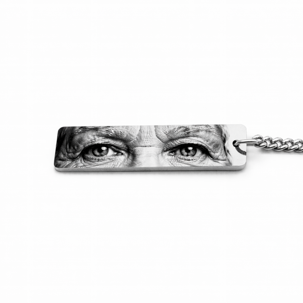 a silver keychain pendant featuring an elderly woman's eyes in black and white