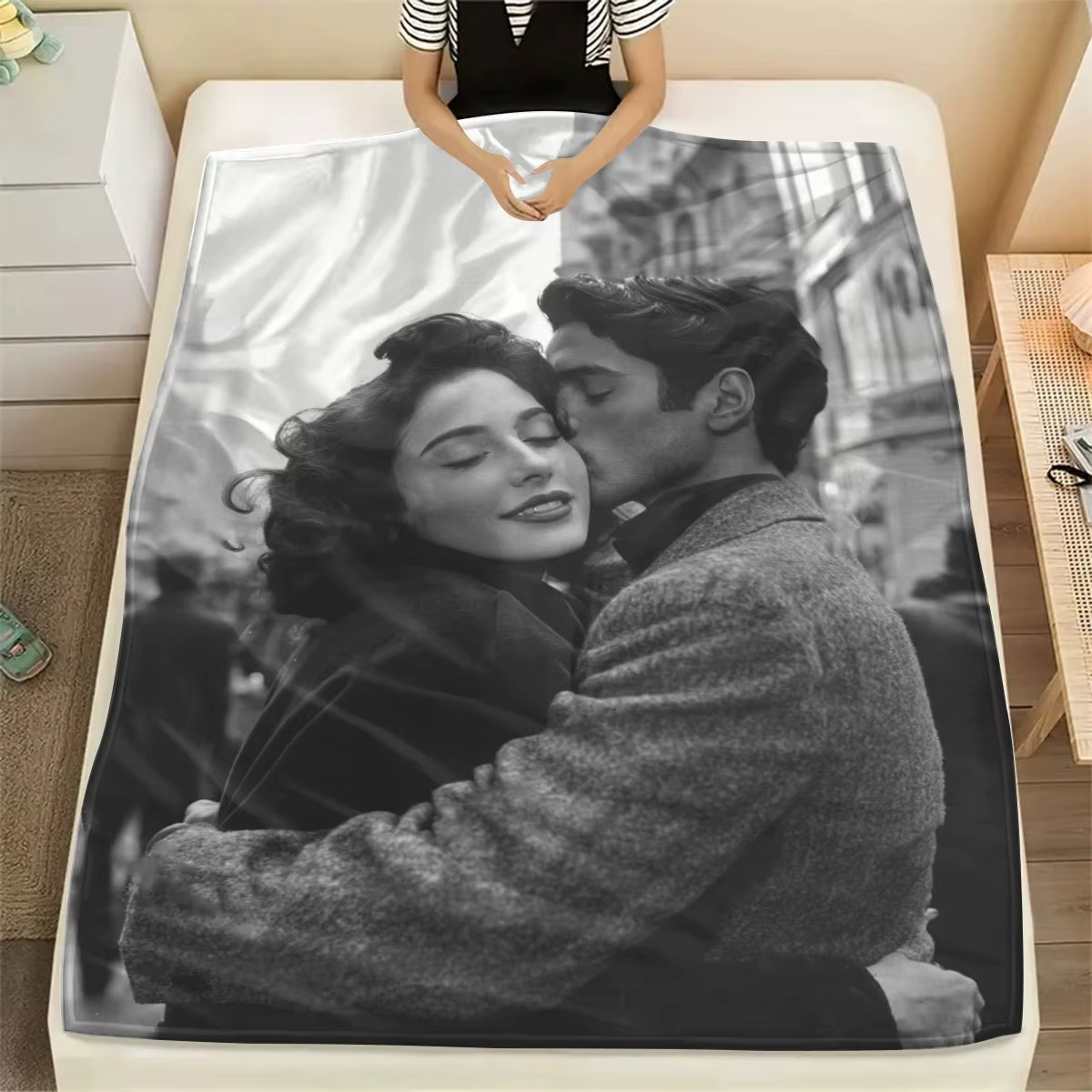 a woman laying beneath a blanket that is printed with a black and white photo of her and her husband embracing