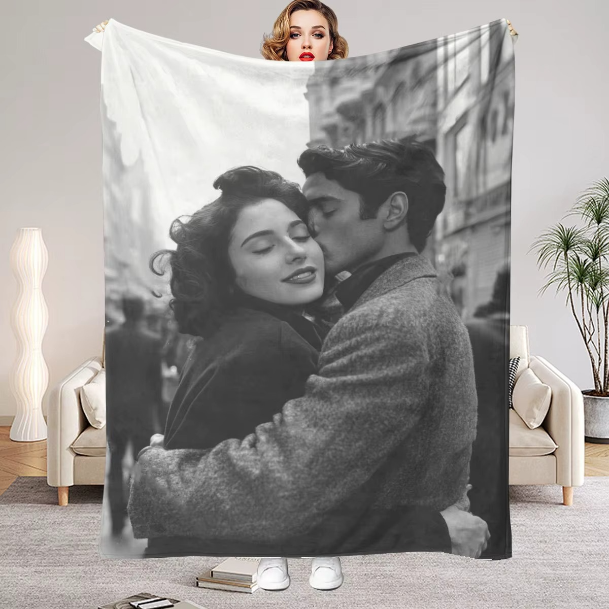 a woman holding up a blanket that is printed with a black and white photo of her and her husband embracing
