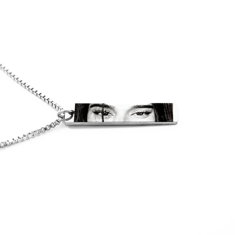 a silver necklace chain and pendant featuring the eyes of a young woman in black and white