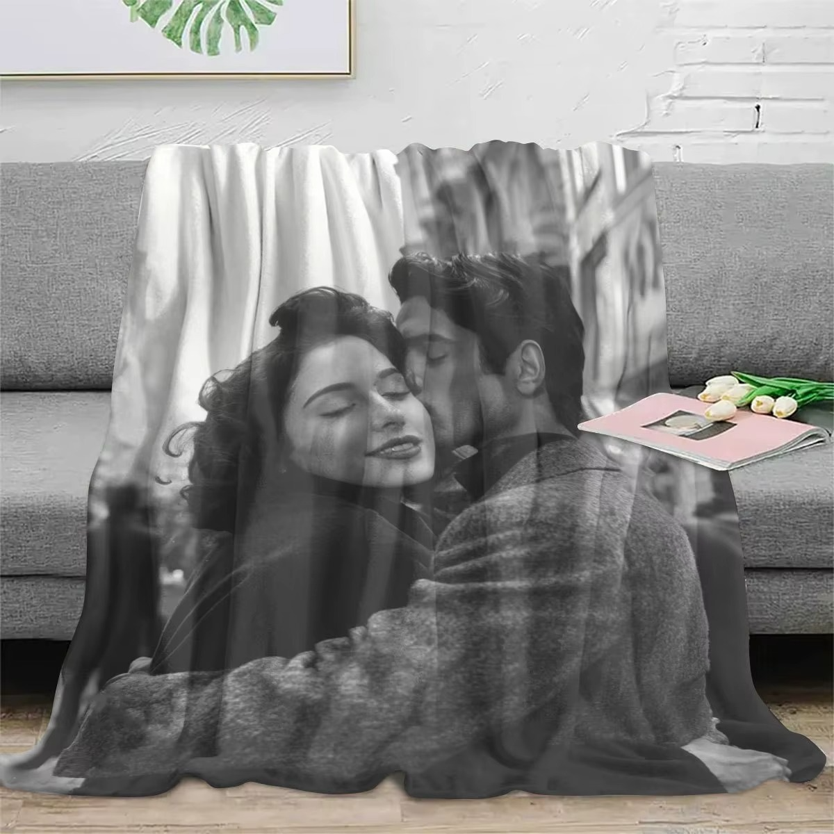 a blanket printed with a greyscale photo of a couple embracing is draped over a gray couch