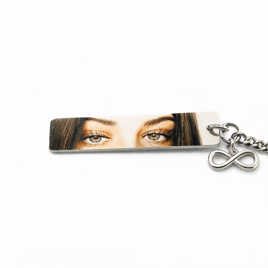 a silver keychain featuring a photo of a woman's eyes in vivid color with an infinity charm attached